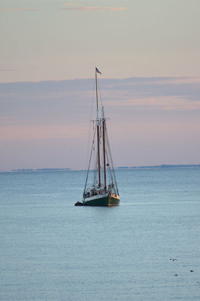 A small boat along with a flag over it in the middle of sea